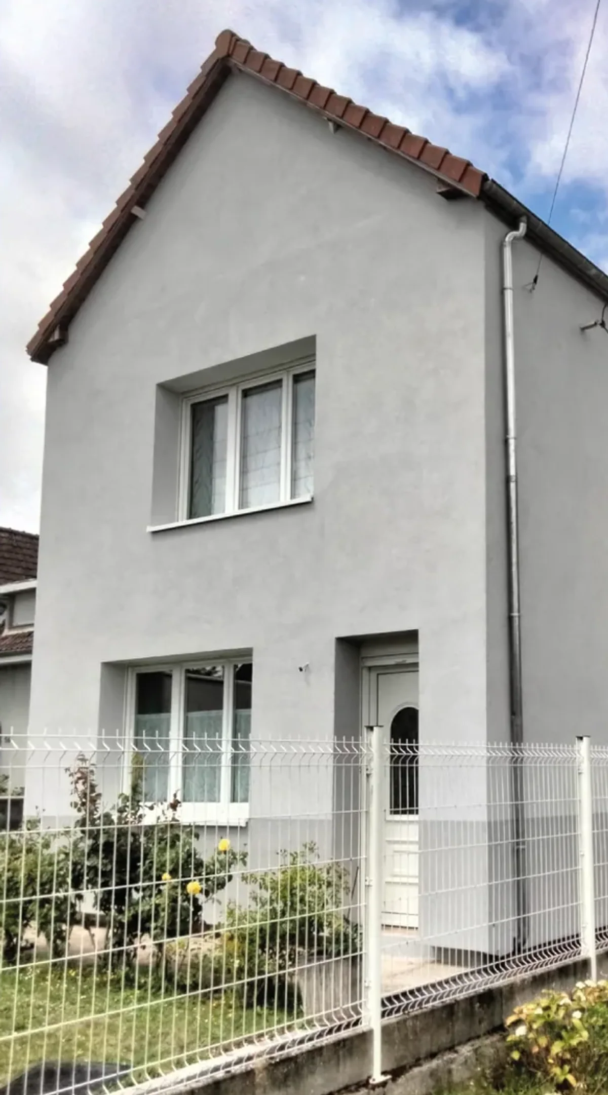 Façade claire enduite et encadrements gris sur une maison rénovée